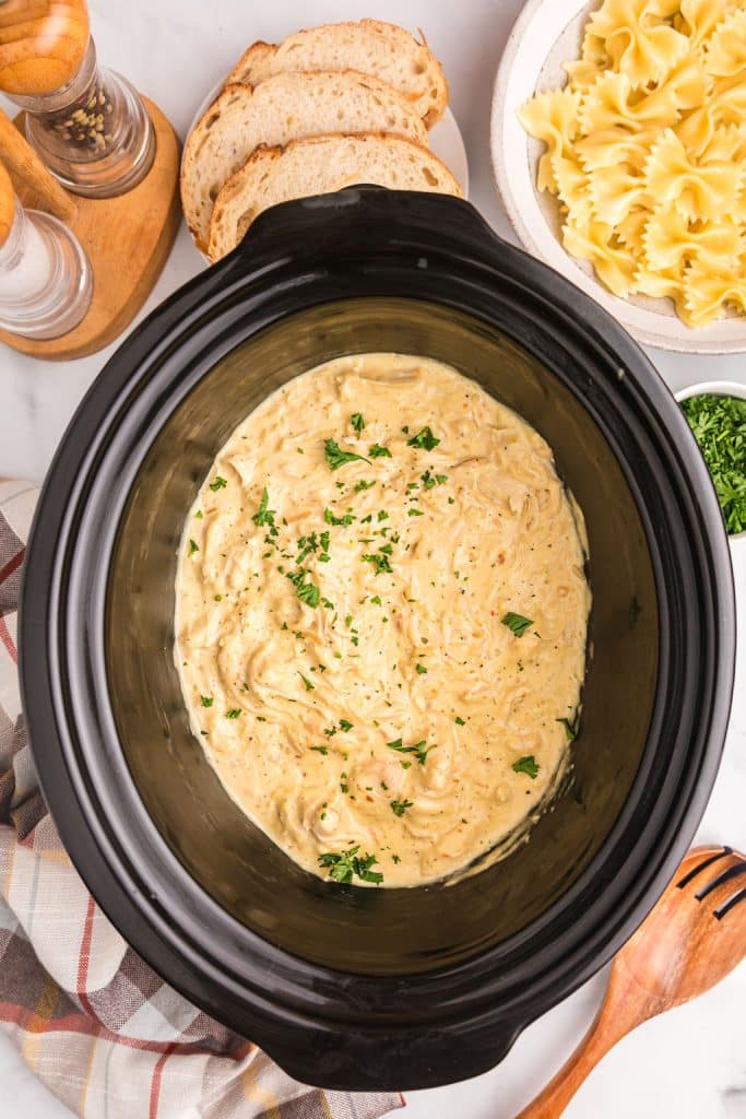 overhead shot of creamy italian chicken in a black slow cooker.