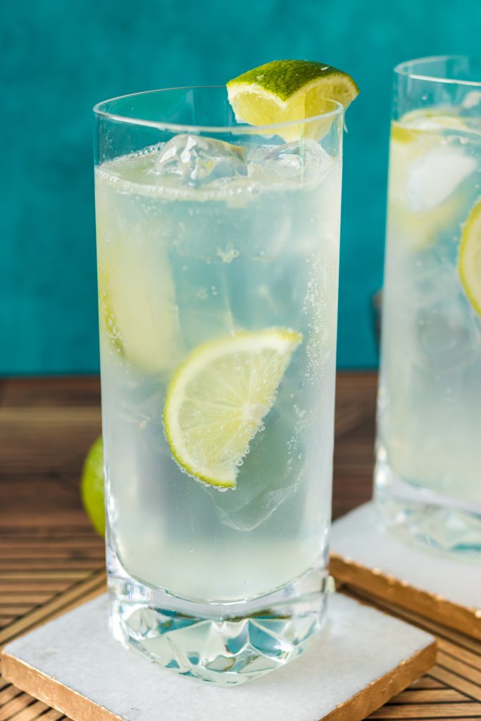 a frosty ranch water cocktail with lime wedges on a coaster