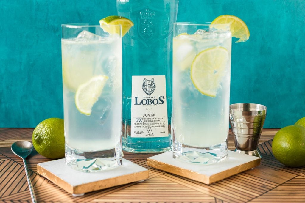 two tequila cocktails with lime garnish on coasters