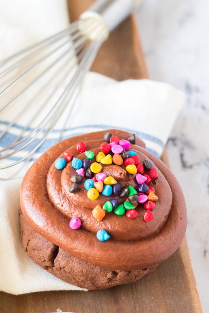 cosmic brownie cookie topped with rainbow chips sitting next to a whisk.
