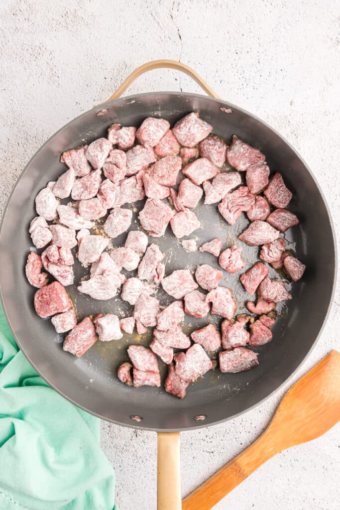 floured stew beef pieces in a skillet.