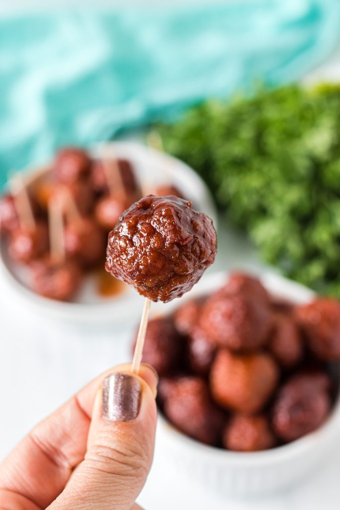 hand holding a meatball on a toothpick.