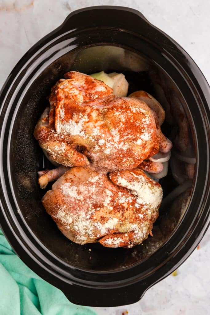 Raw Cornish hens seasoned with spices in a crockpot.