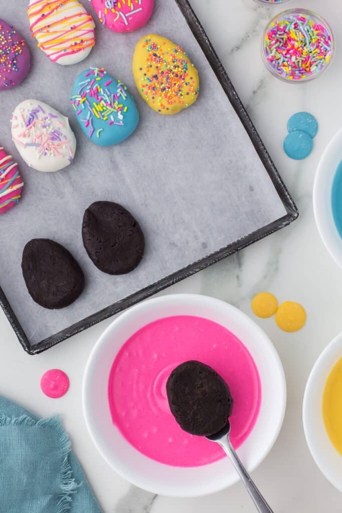 fork dipping an egg shaped truffle into pink candy melts.