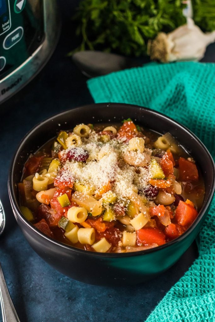 bowl of minestrone soup next to a deal napkin.