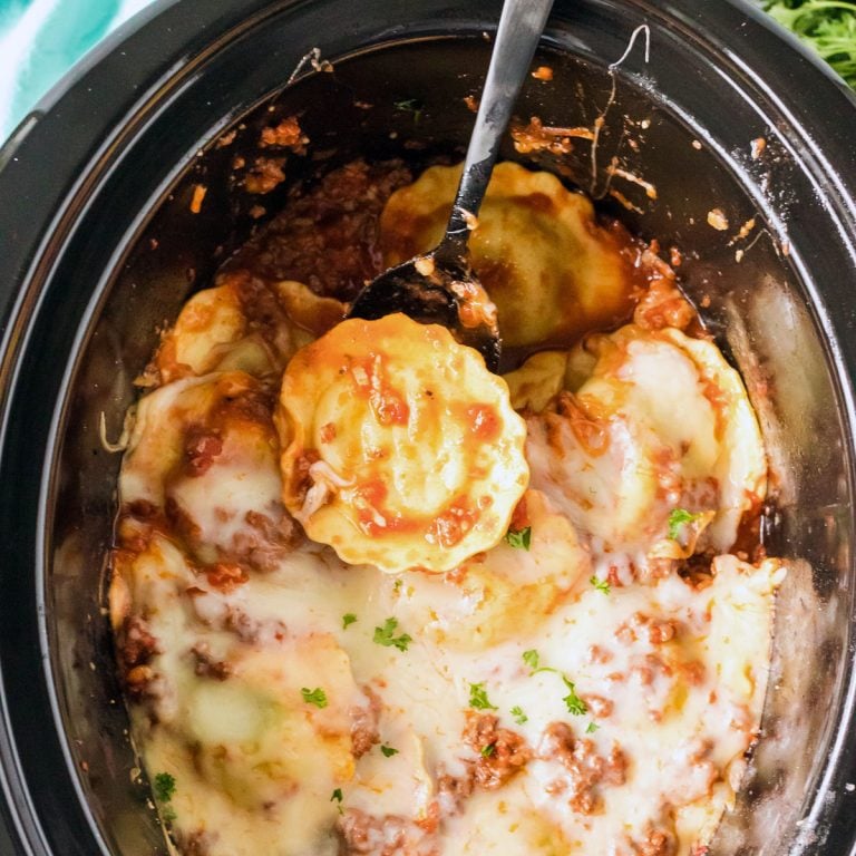 spoon scooping ravioli from a slow cooker.