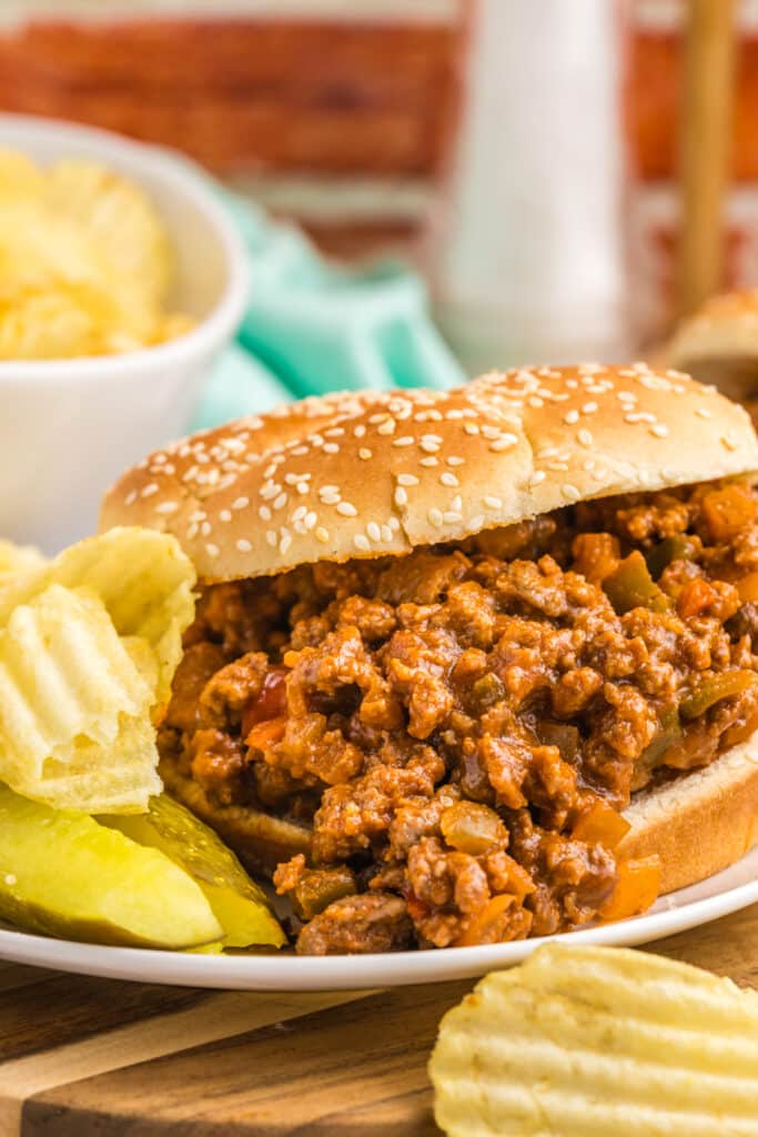 sloppy joe on a sesame seed bun with chips & pickle.