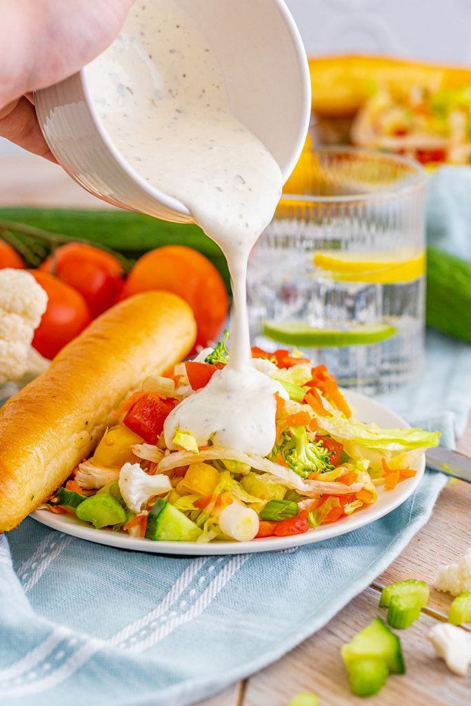 salad dressing pouring onto a side veggie salad.