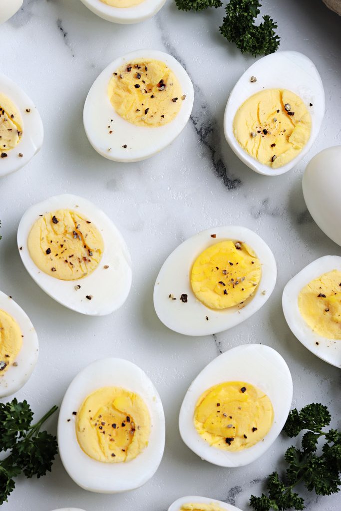 overhead shot of peeled, sliced, and peppered hard boiled eggs.