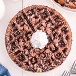 overhead shot of chocolate waffle with chocolate sauce, chocolate chips, and whipped cream.
