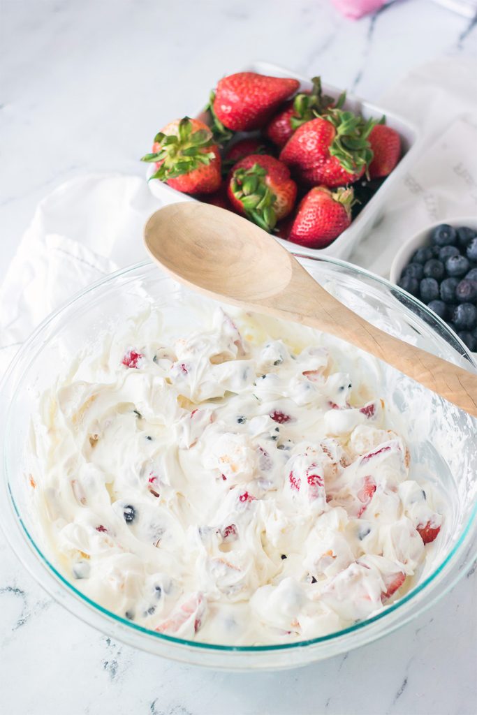 overhead shot of a mixing bowl and wooden spoon filled with berry fluff salad.