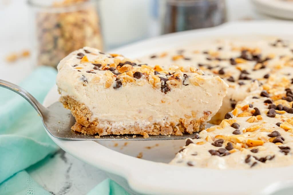 lifting a slice of peanut butter pie from a dish.