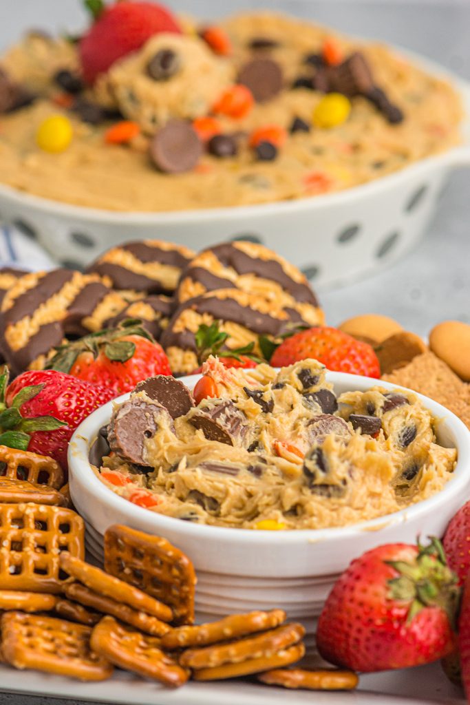 peanut butter cookie dough dip surrounded by pretzels, strawberries, and cookies. 