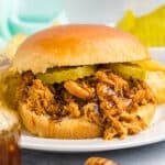 hot honey shredded chicken sandwich on a brioche bun topped with pickles.