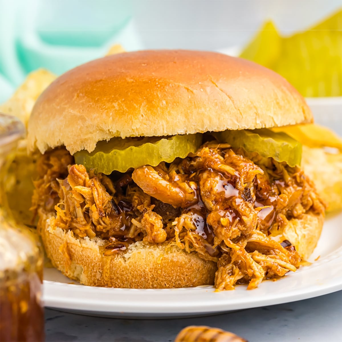 hot honey shredded chicken sandwich on a brioche bun topped with pickles.