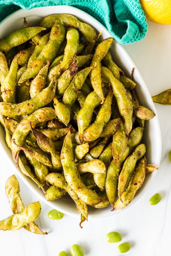 overhead shot of roasted edamame in a white bowl.