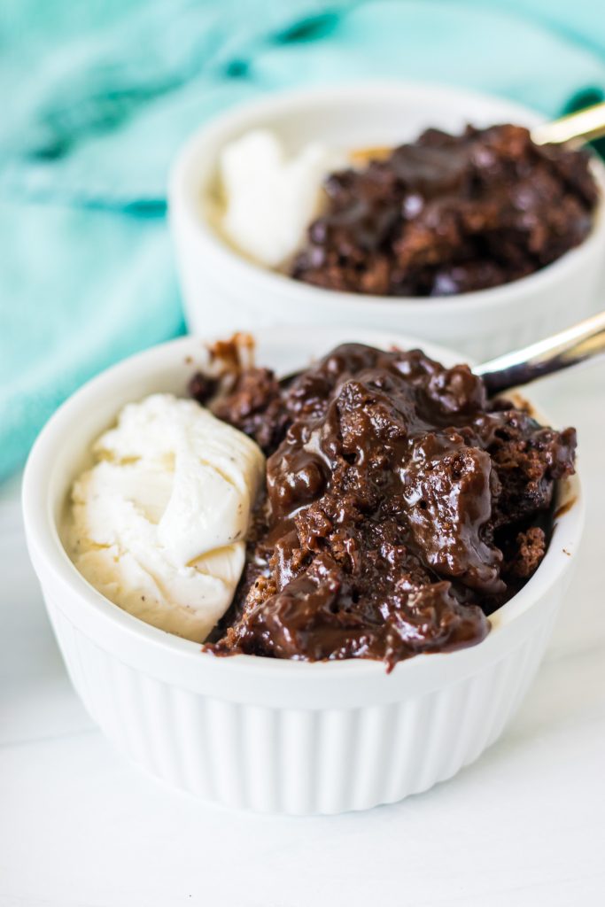 white bowl filled with gooey crockpot lava cake and vanilla ice cream.