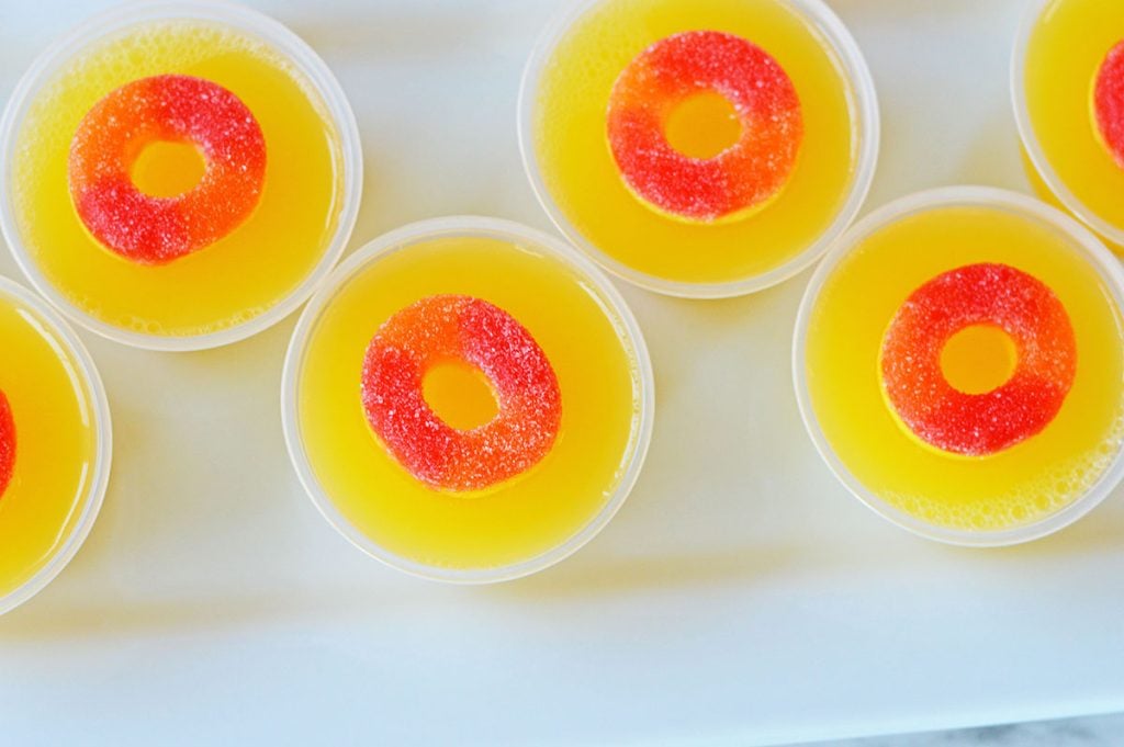 closeup overhead shot of 5 fuzzy navel jello shots on a white plate.