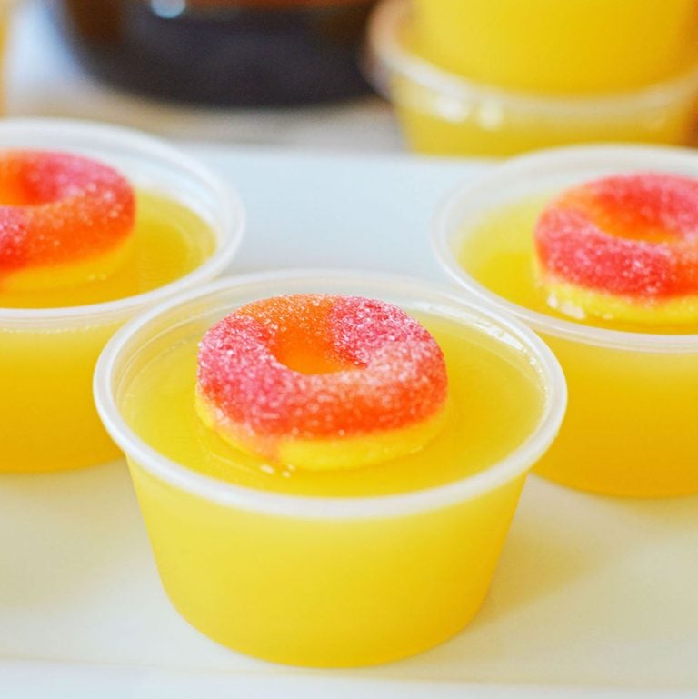closeup of a fuzzy navel jello shot topped with a peach ring candy.