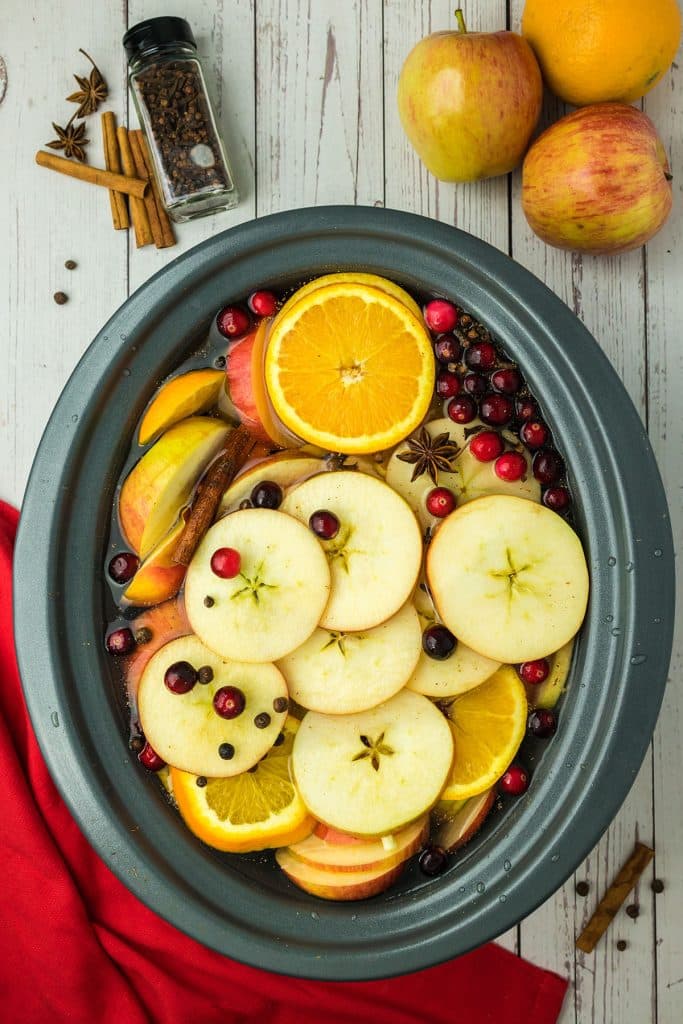 overhead shot of sliced fruit in a slow cooker making cider.