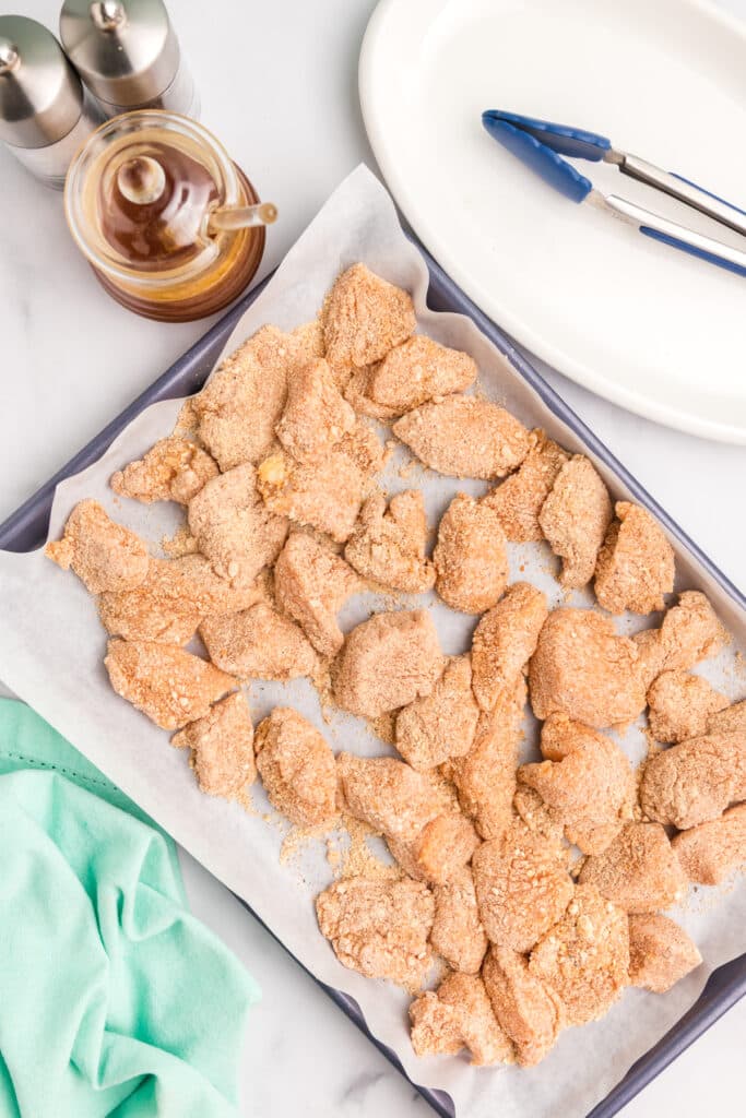 raw, breaded chicken on a baking sheet.