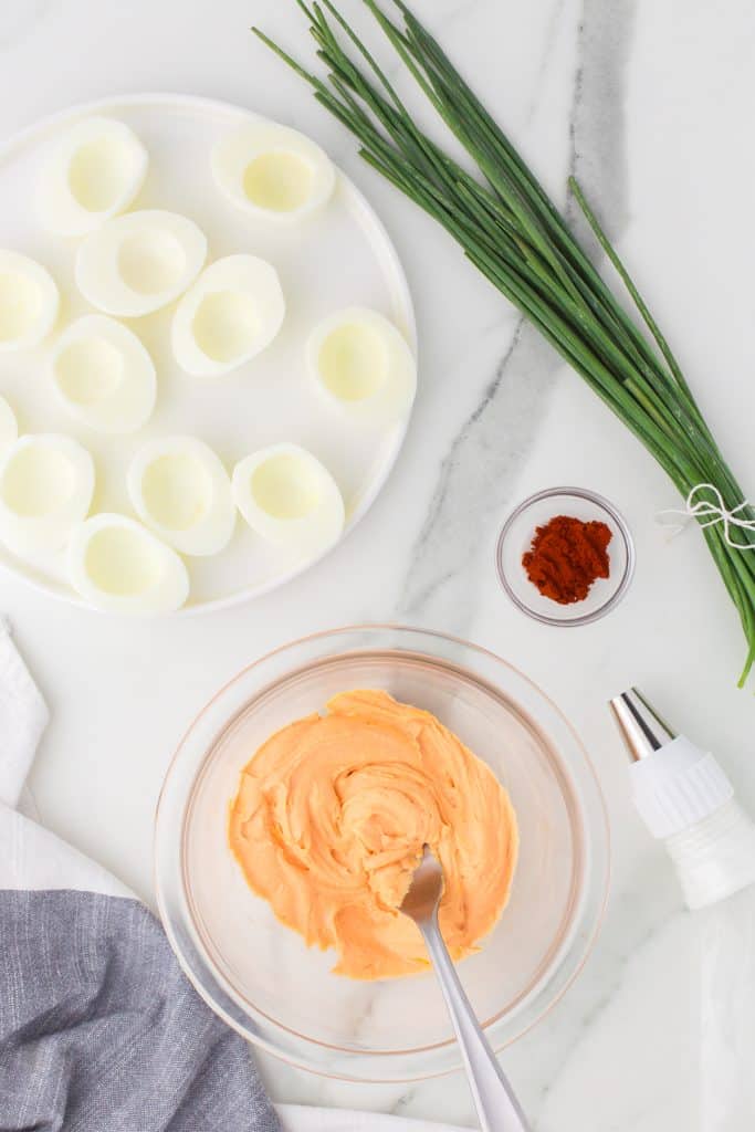 overhead shot of deviled egg filling next to halved eggs.