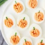 pumpkin shaped deviled eggs on a white platter.