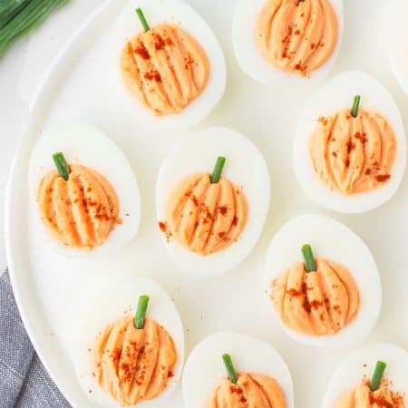pumpkin shaped deviled eggs on a white platter.