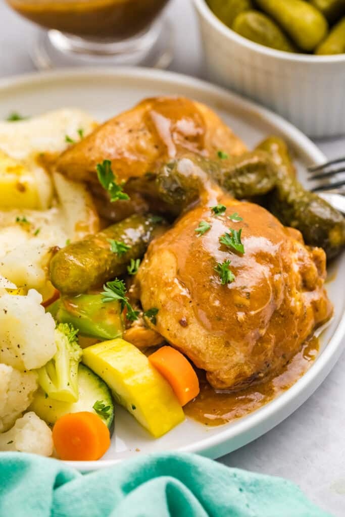 plate of pickle chicken, veggies, and mashed potatoes on a plate.
