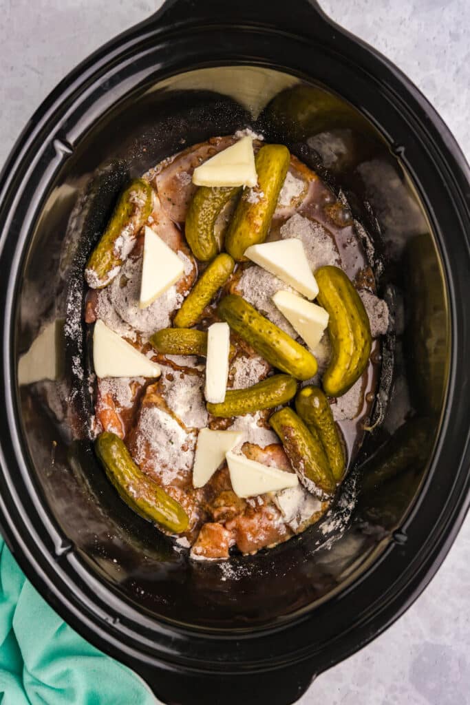 butter, pickles, and chicken in a slow cooker.