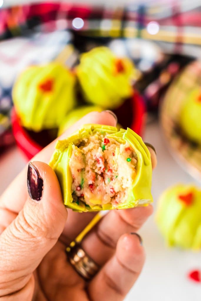 hand holding an oreo cookie truffle with a bite taken out of it.