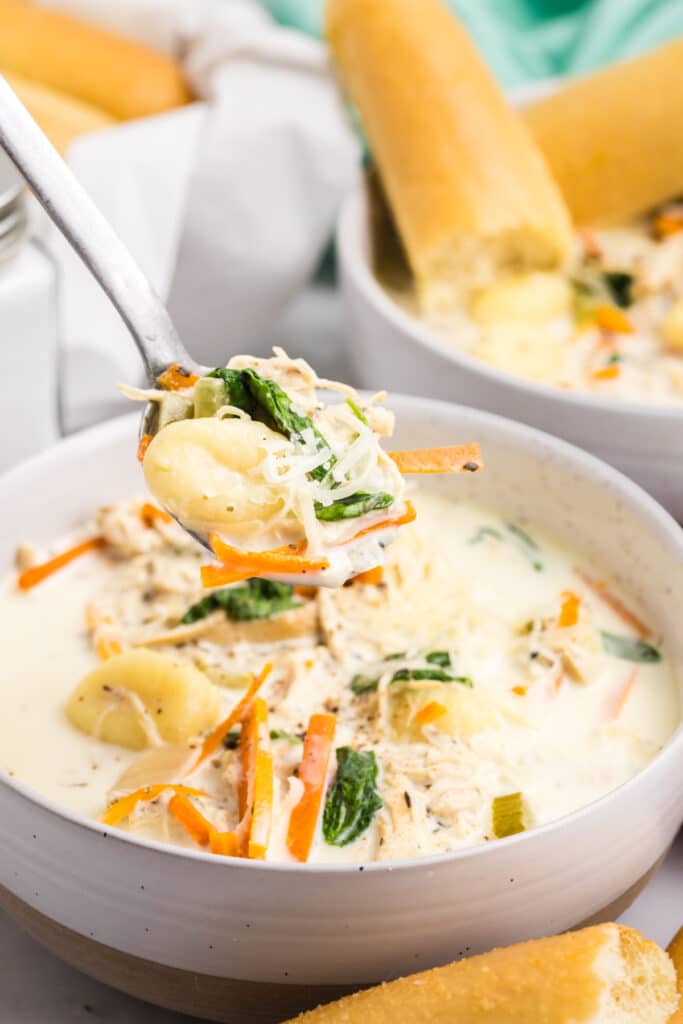 spoon lifting a bite of chicken gnocchi soup from a bowl.