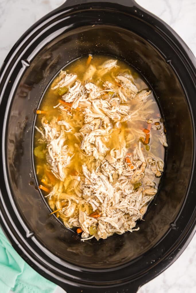 overhead shot of shredded chicken in a black crockpot.