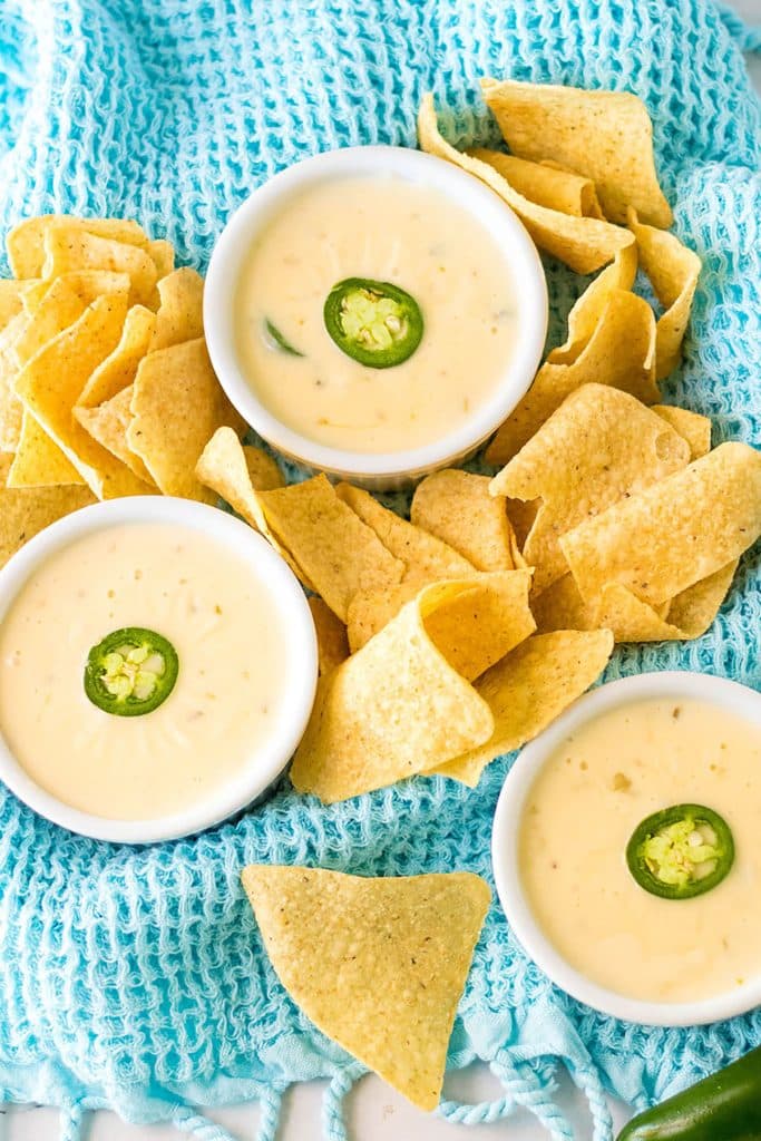 overhead shot of three bowls of queso blanco and tortilla chips.