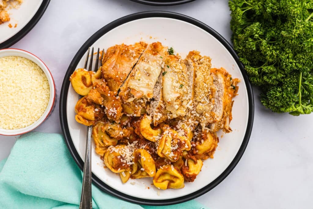 plated sliced chicken parmesan with tortellini.