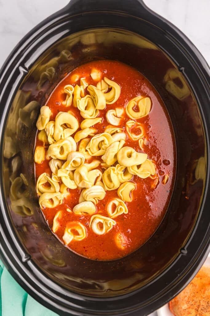 overhead shot of tortellini in a crockpot with marinara.