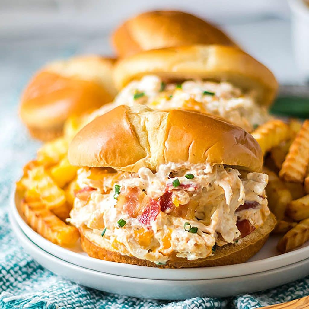 slow cooker chicken bacon ranch sandwiches on a white plate with fries.