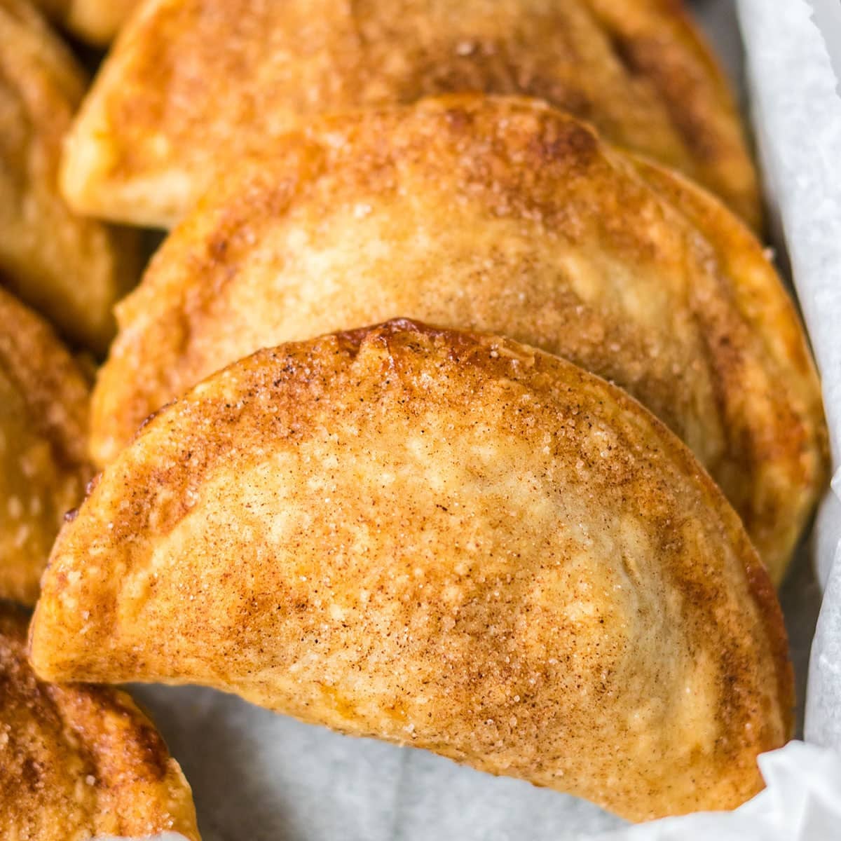 closeup of a stack of 3 caramel apple empanadas.