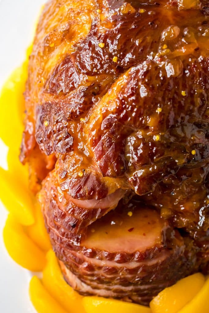 spiral sliced ham surrounded by peach slices.