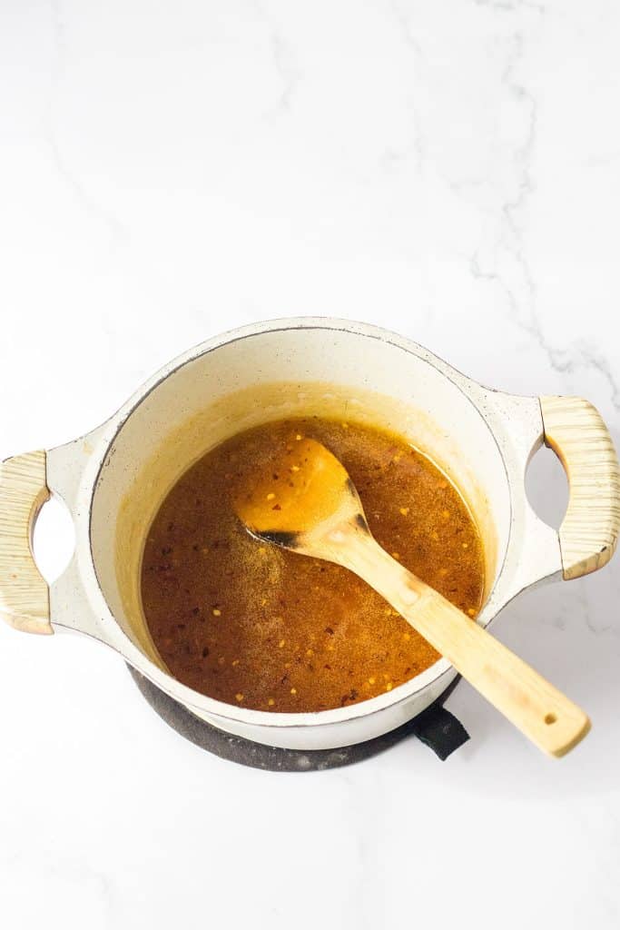 saucepan with glaze and a wooden spoon sticking out.