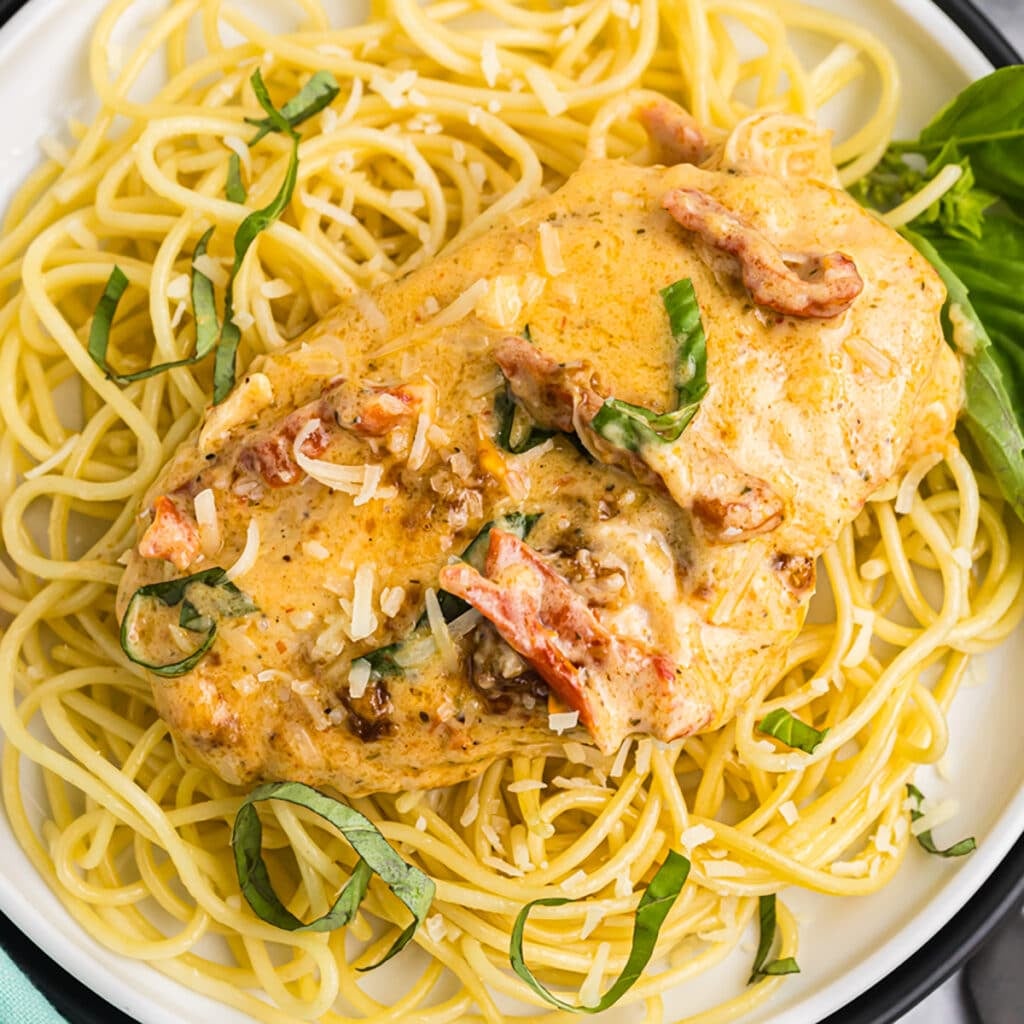 overhead shot of marry me chicken on a bed of noodles.