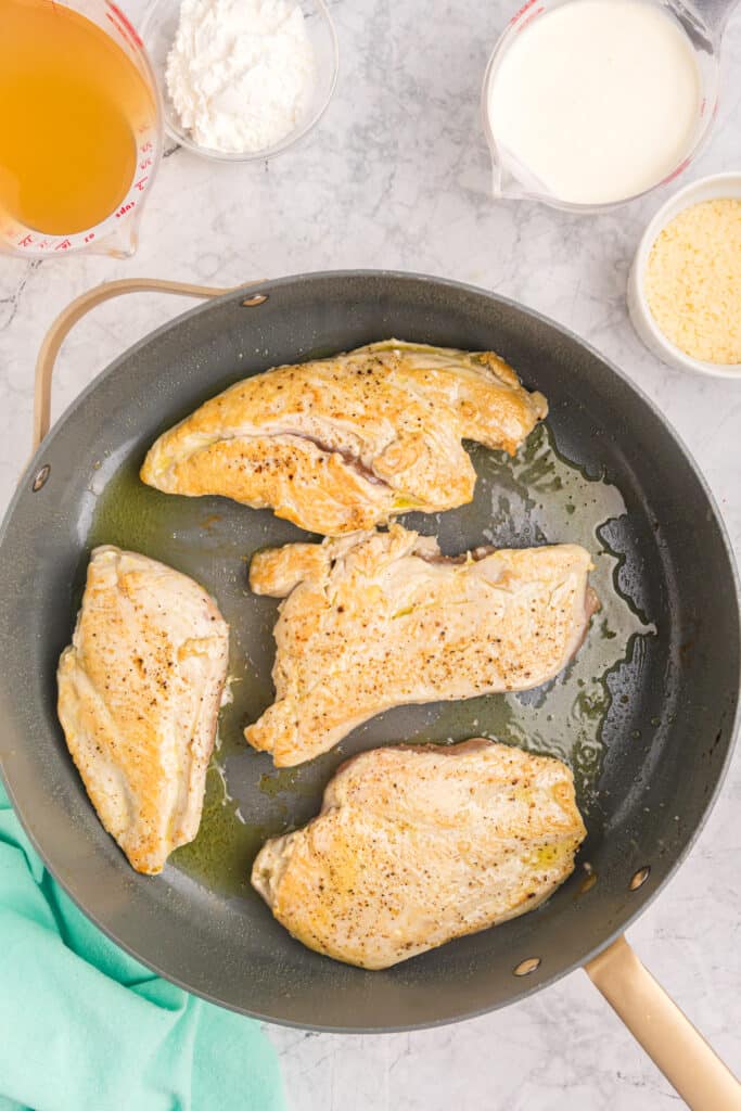 overhead shot of seared chicken breasts in a skillet.