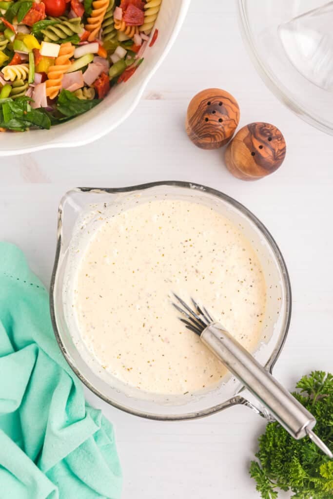 creamy italian dressing with a whisk in a bowl.