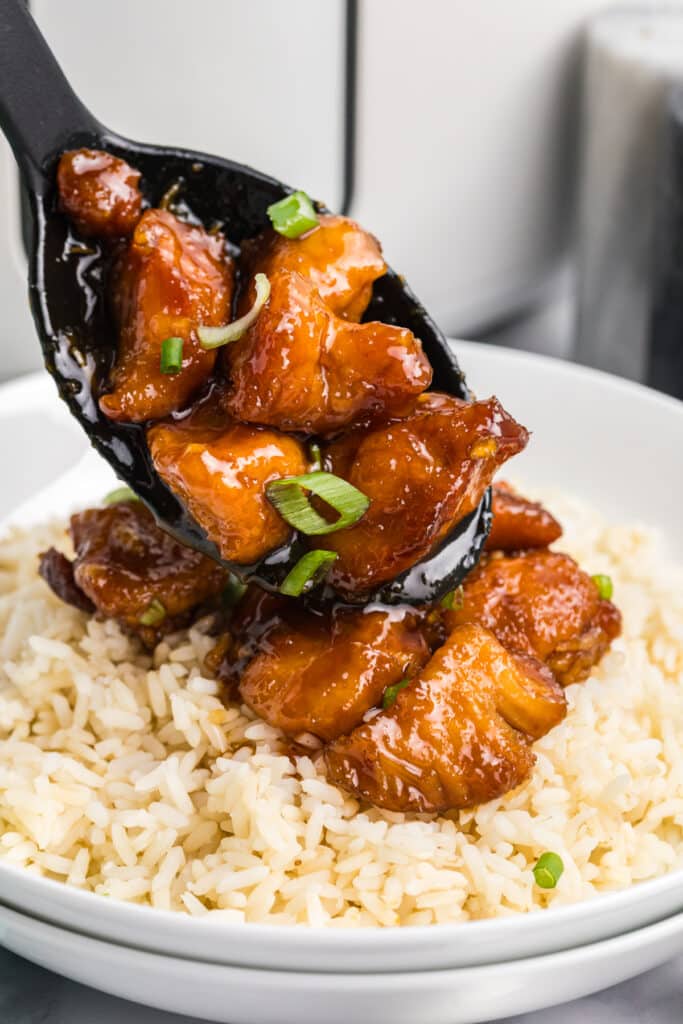 firecracker chicken being spooned over white rice.