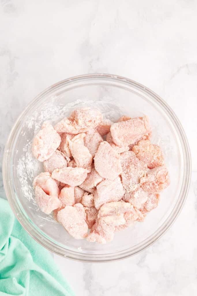 chicken breast pieces coated in cornstarch in a bowl.