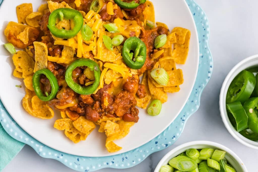 plate of frito chili pie topped with jalapeno slices.