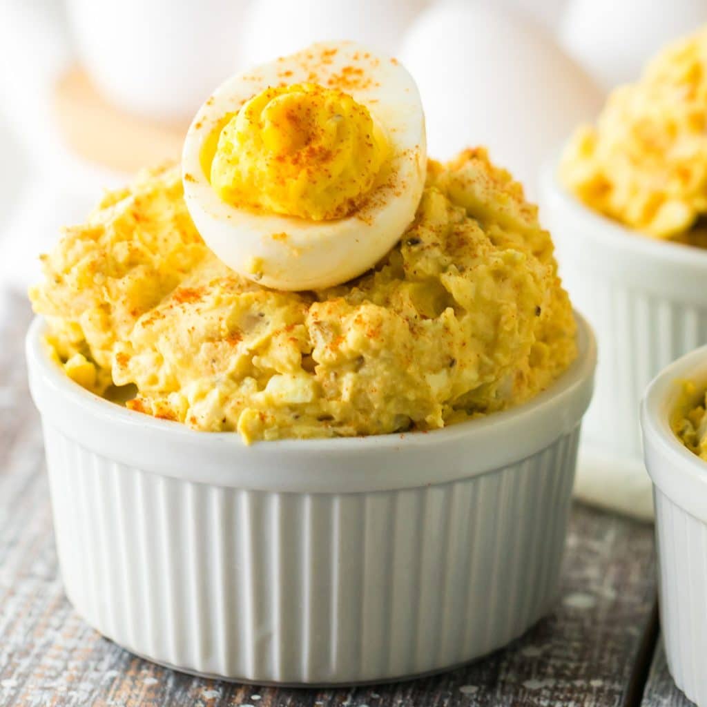 white bowl filled with potato salad topped with a deviled egg.