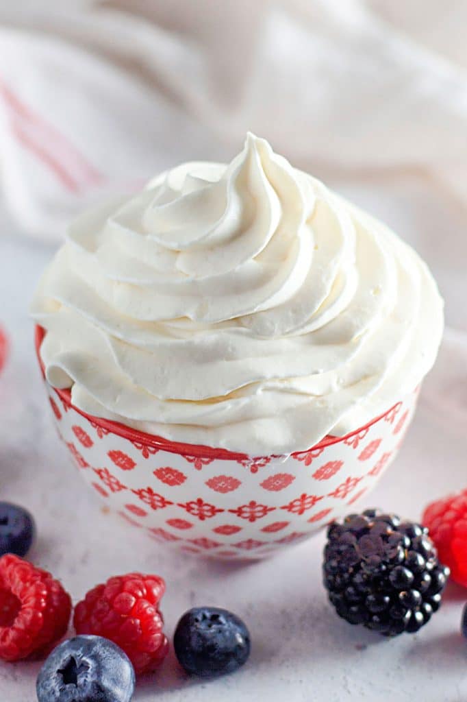 bowl of homemade cool whip surrounded by berries.