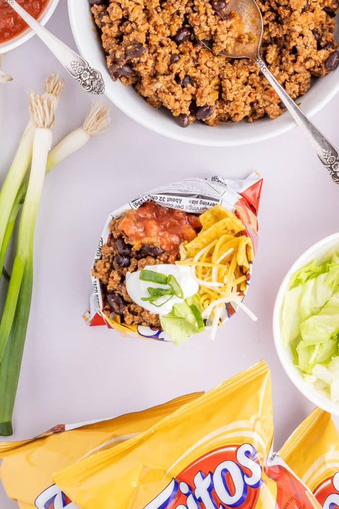 overhead shot of a frito bag being filled with taco toppings.
