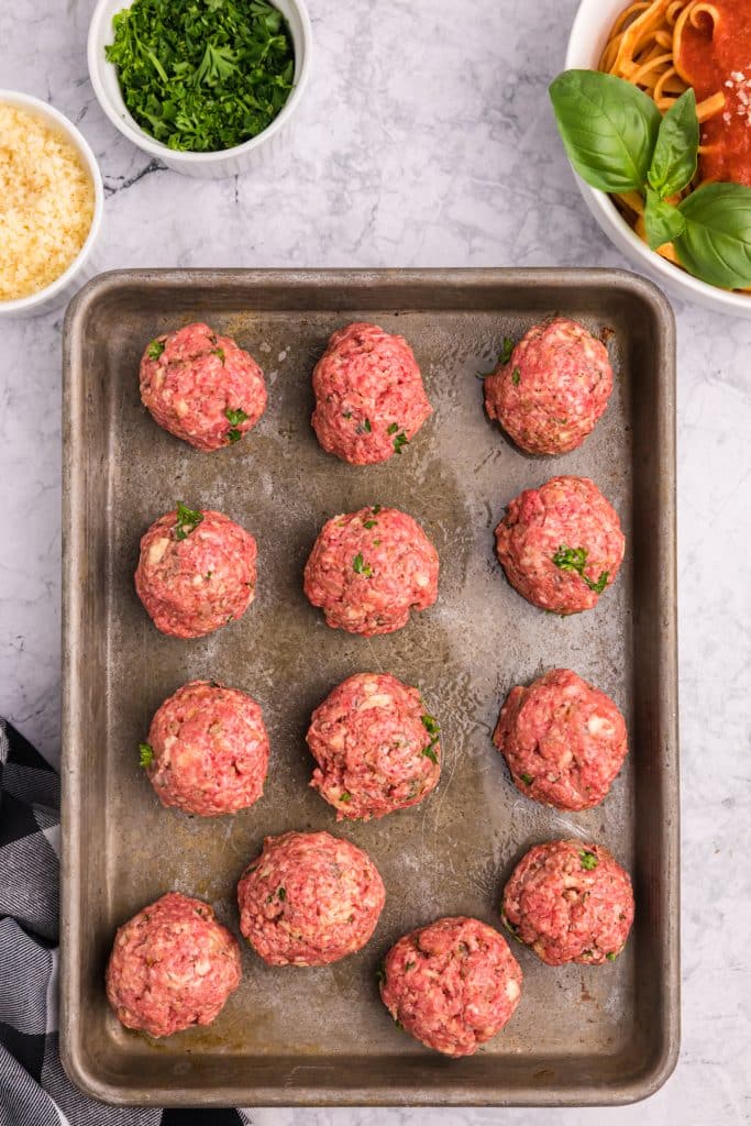 raw meatballs on a baking sheet.